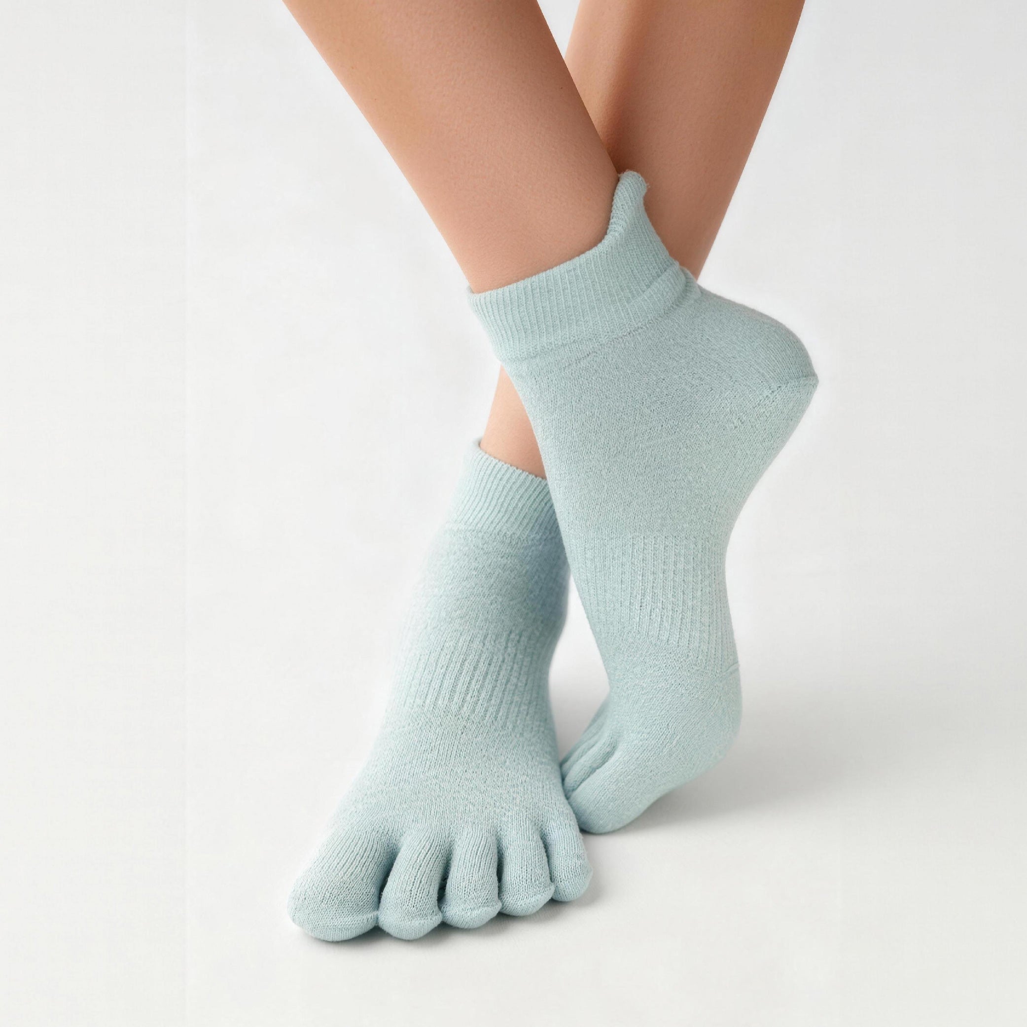Light blue five-finger socks worn by a person on a light gray background