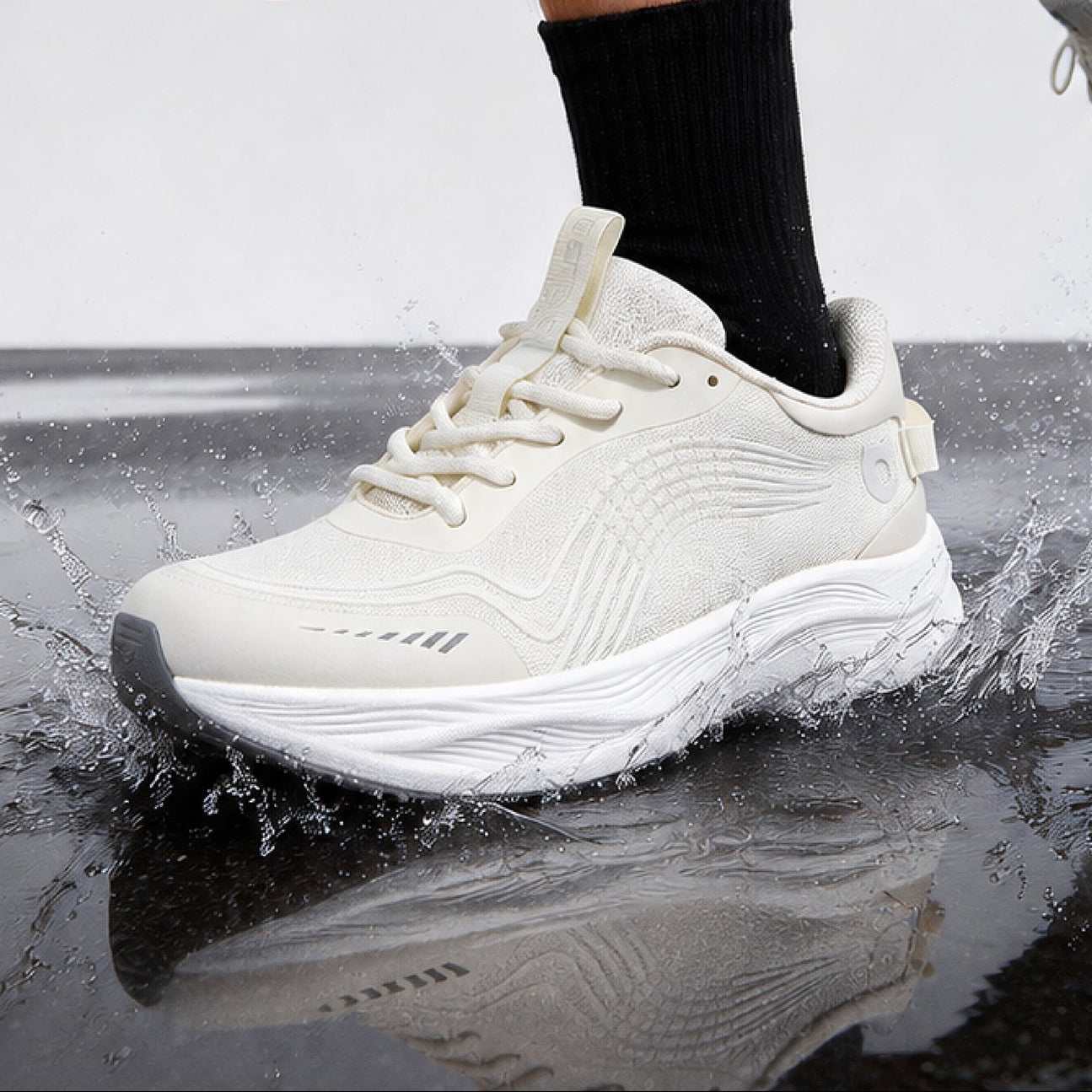Runner wearing white EFISIO Airfoil II Athletic Shoes, mid-stride on a wet reflective surface with a solid gray background