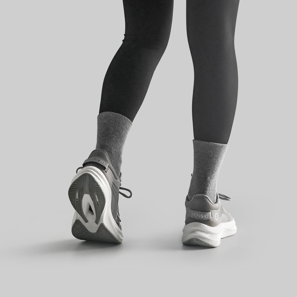 Person wearing black leggings and gray EFISIO Airfoil II Athletic Shoes on a light gray background