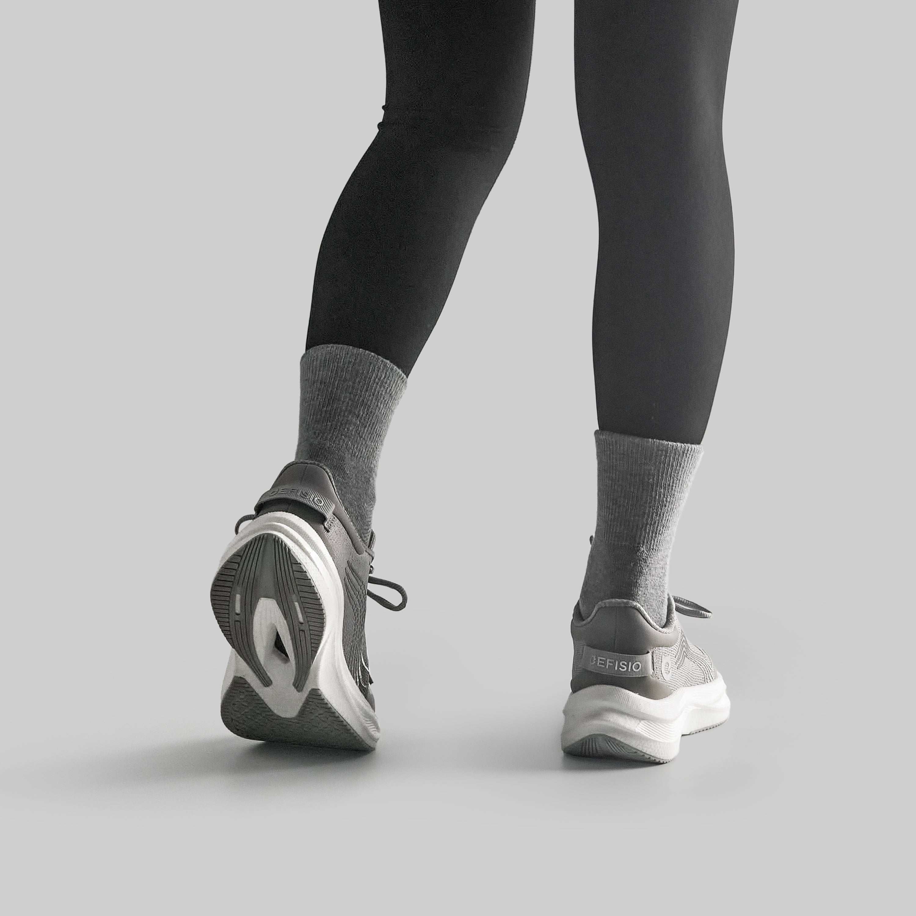 Person wearing black leggings and gray EFISIO Airfoil II Athletic Shoes on a light gray background