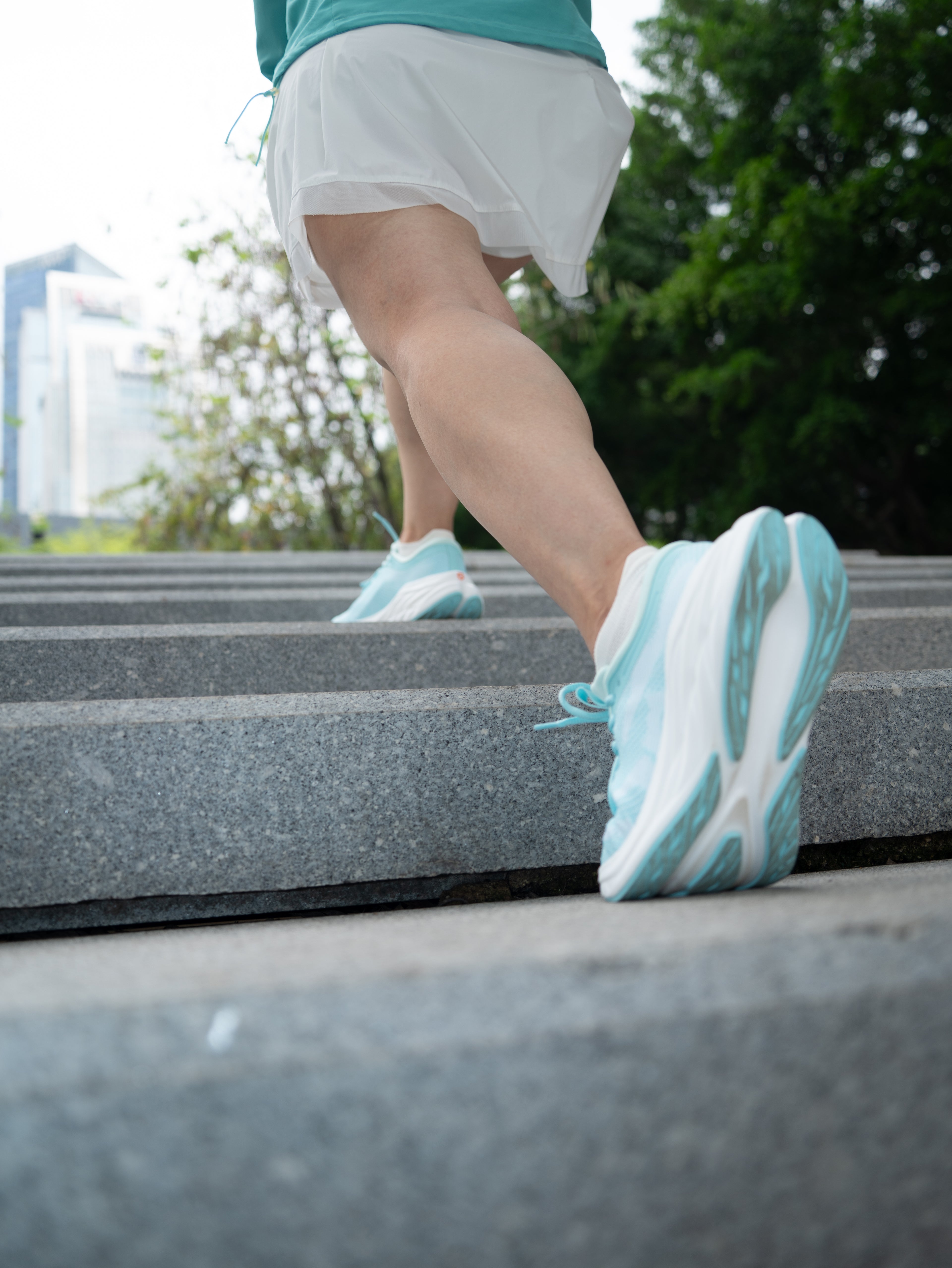 Runner sprinting up outdoor concrete steps wearing light blue EFISIO Airheart athletic shoes