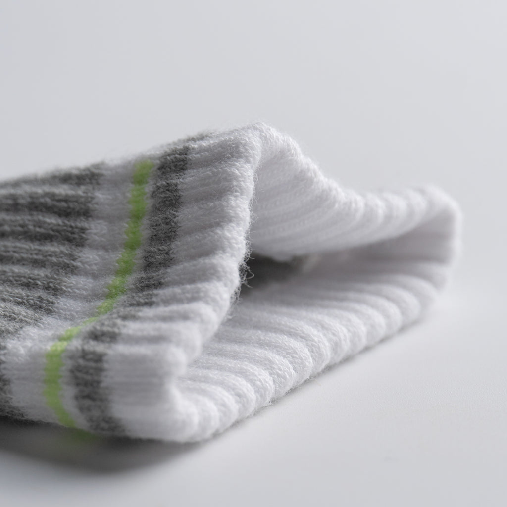 Folded gray and white EFISIO All-Day Running sock with green stripe on a light gray background