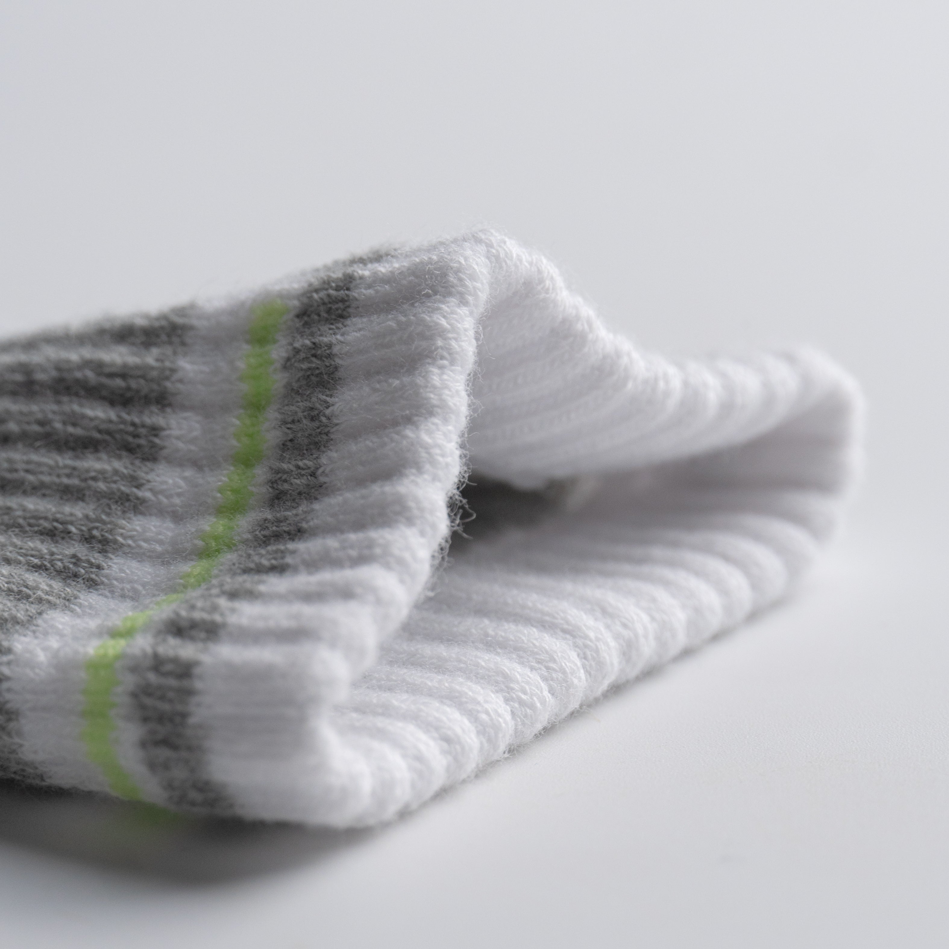 Folded gray and white EFISIO All-Day Running sock with green stripe on a light gray background