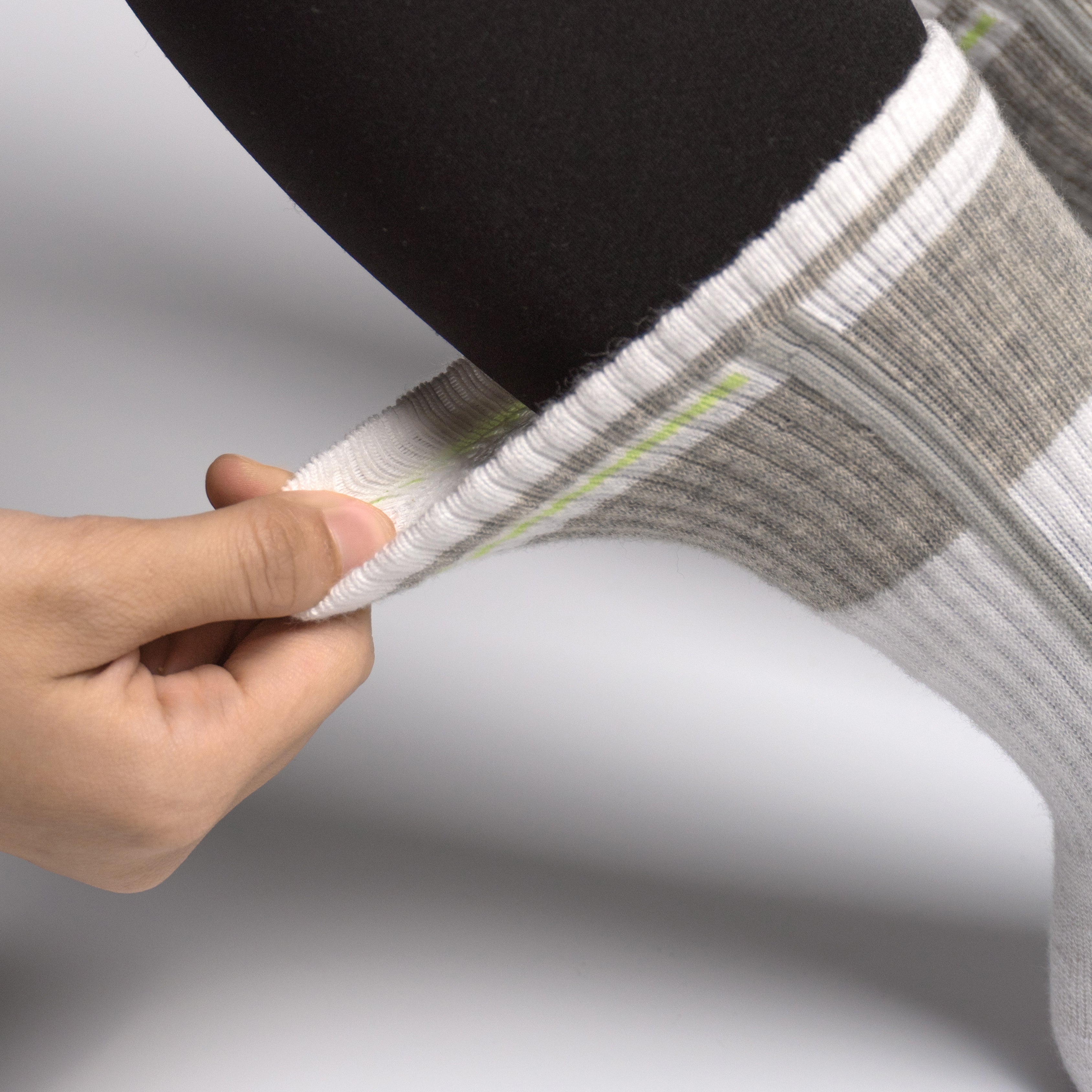 Person holding a gray and white EFISIO All-Day Running sock with a black foot against a light gray background