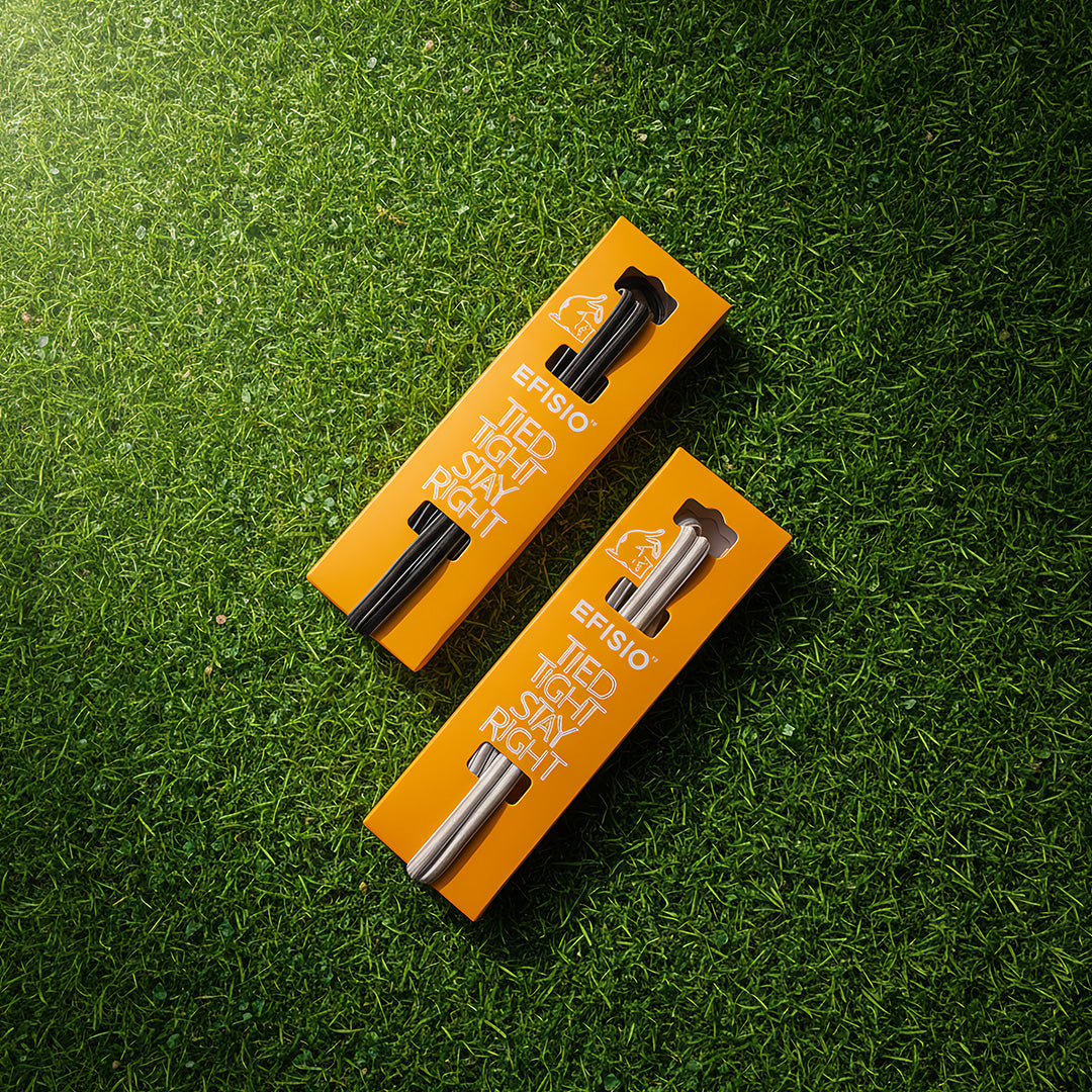 Two orange packaging boxes with black and silver elastic shoelaces on a green grass background