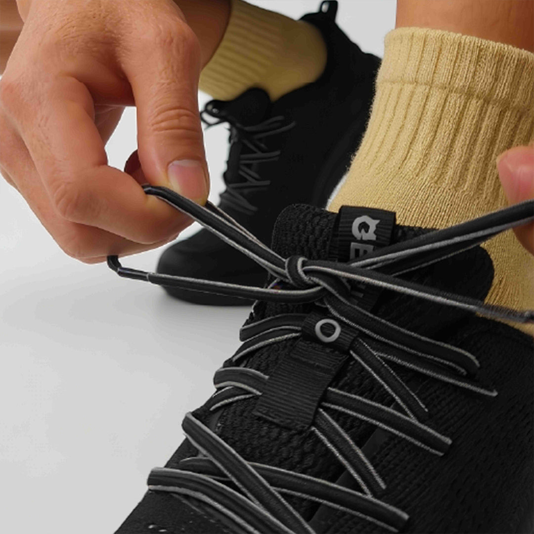 Person tying EFISIO Elastic Shoelaces on a black sneaker with a white background