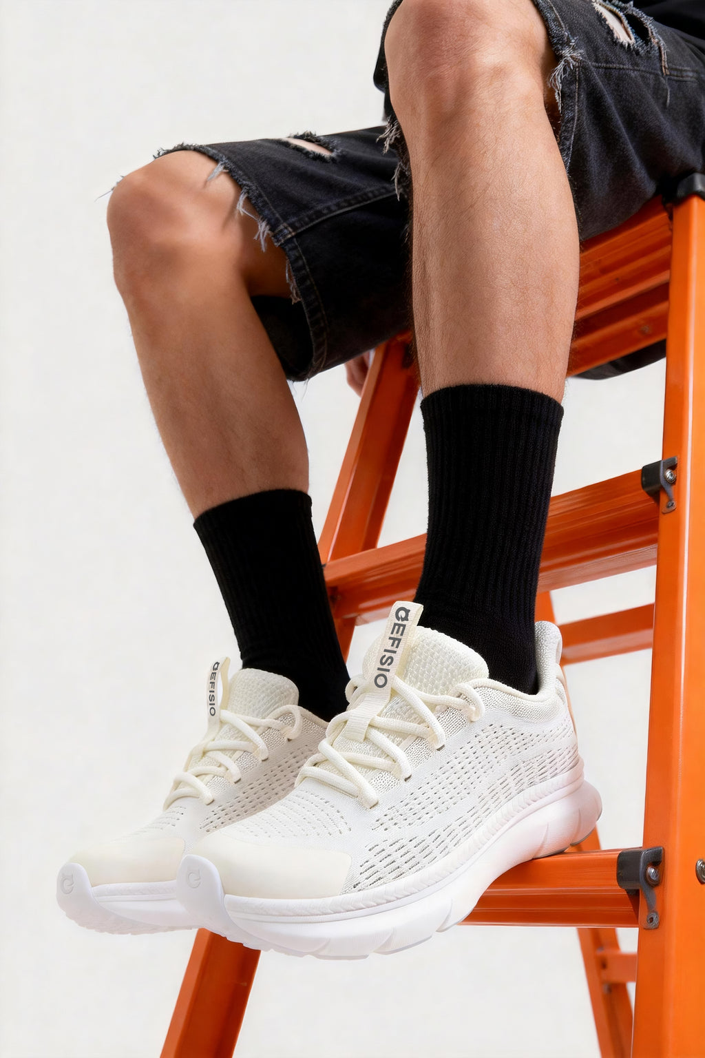 Person wearing EFISIO Flying III Athletic Shoes and sitting on an orange ladder.