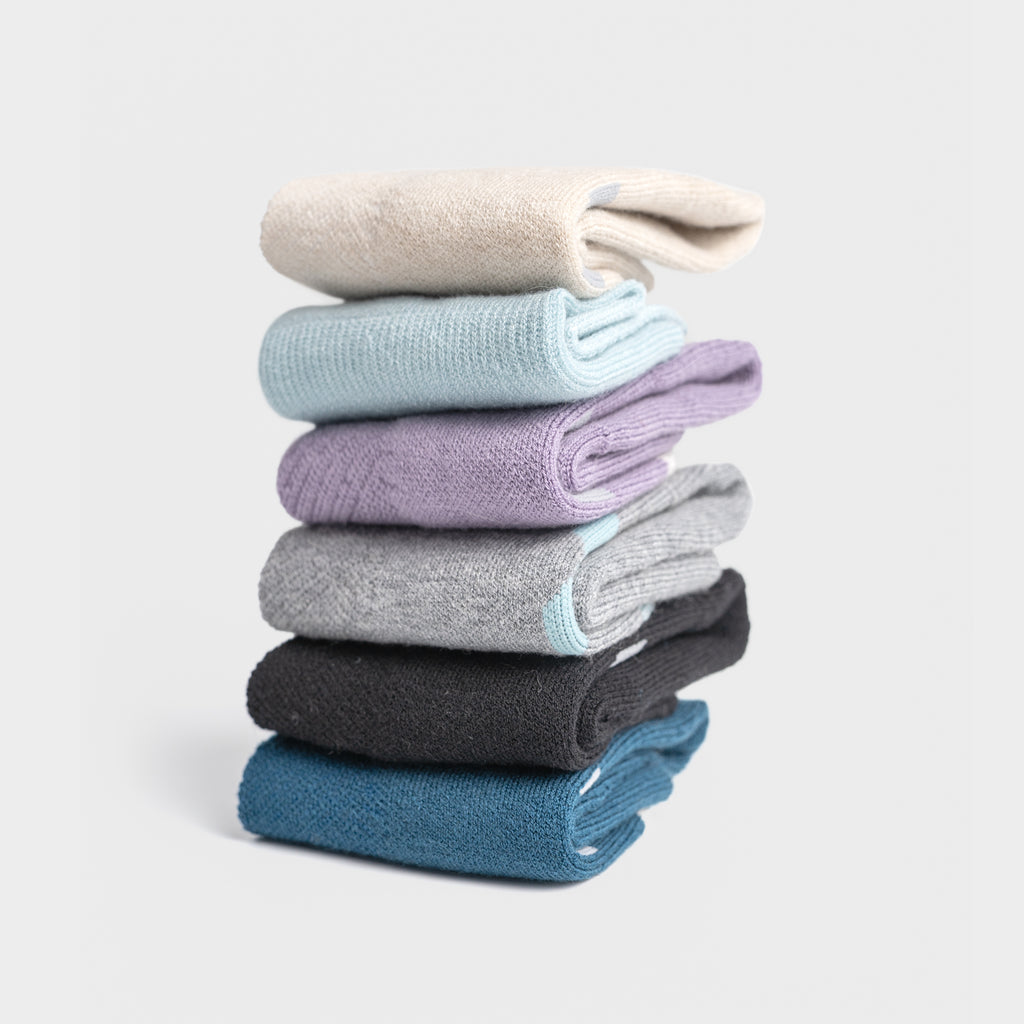 Stack of colorful EFISIO Merino Wool Crew socks on a light gray background